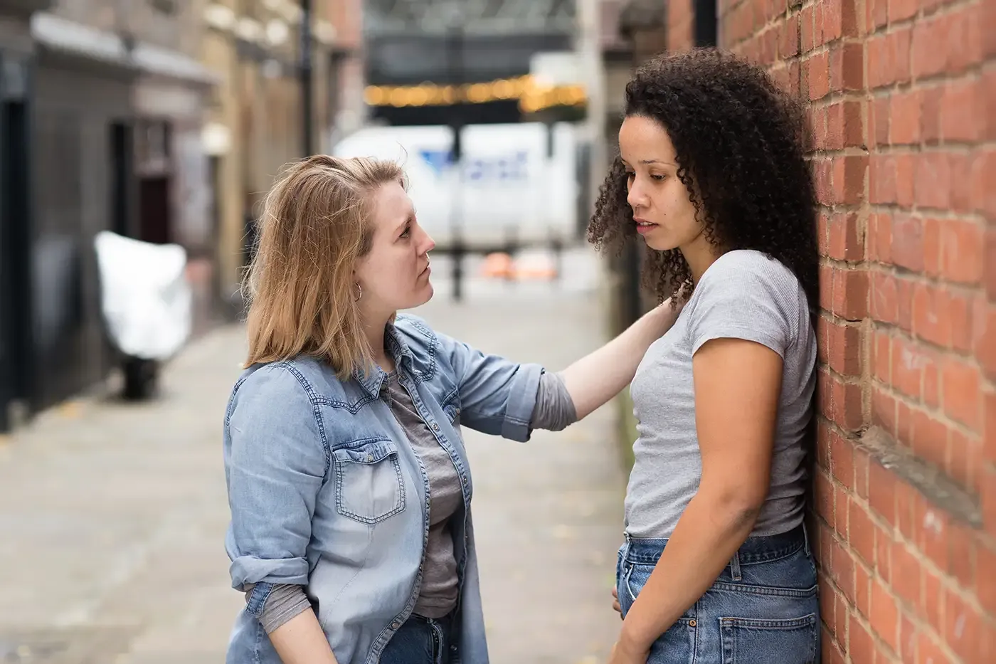 Foto de dos mujeres, tensas, en un callejón.