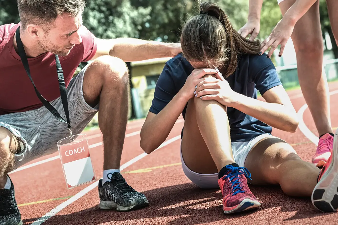 Foto de un entrenador masculino hablando con una joven atleta en la pista de atletismo.