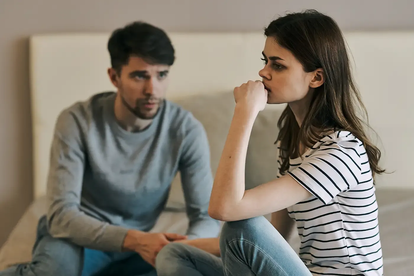 Una pareja, un hombre y una mujer, sentados al borde de la cama en crisis.