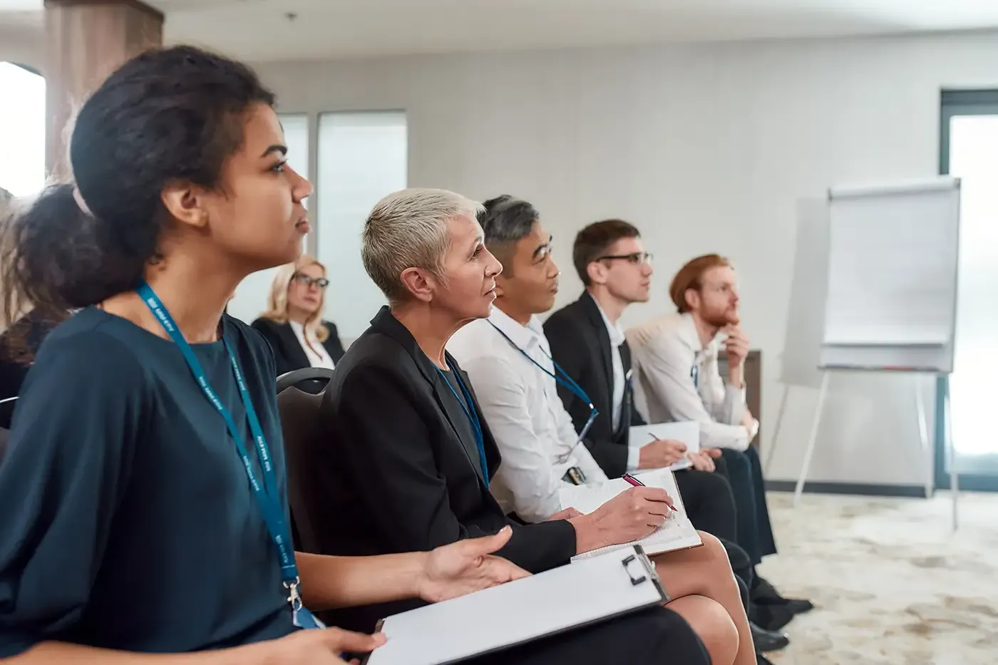 Photo of multi-ethnic audience sitting in a row while listening to presentation at conference hall