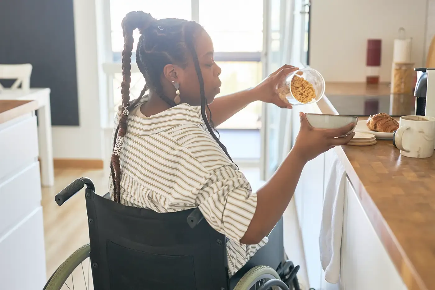 Photo of a woman in a wheelchair getting breakfast in the kitchen