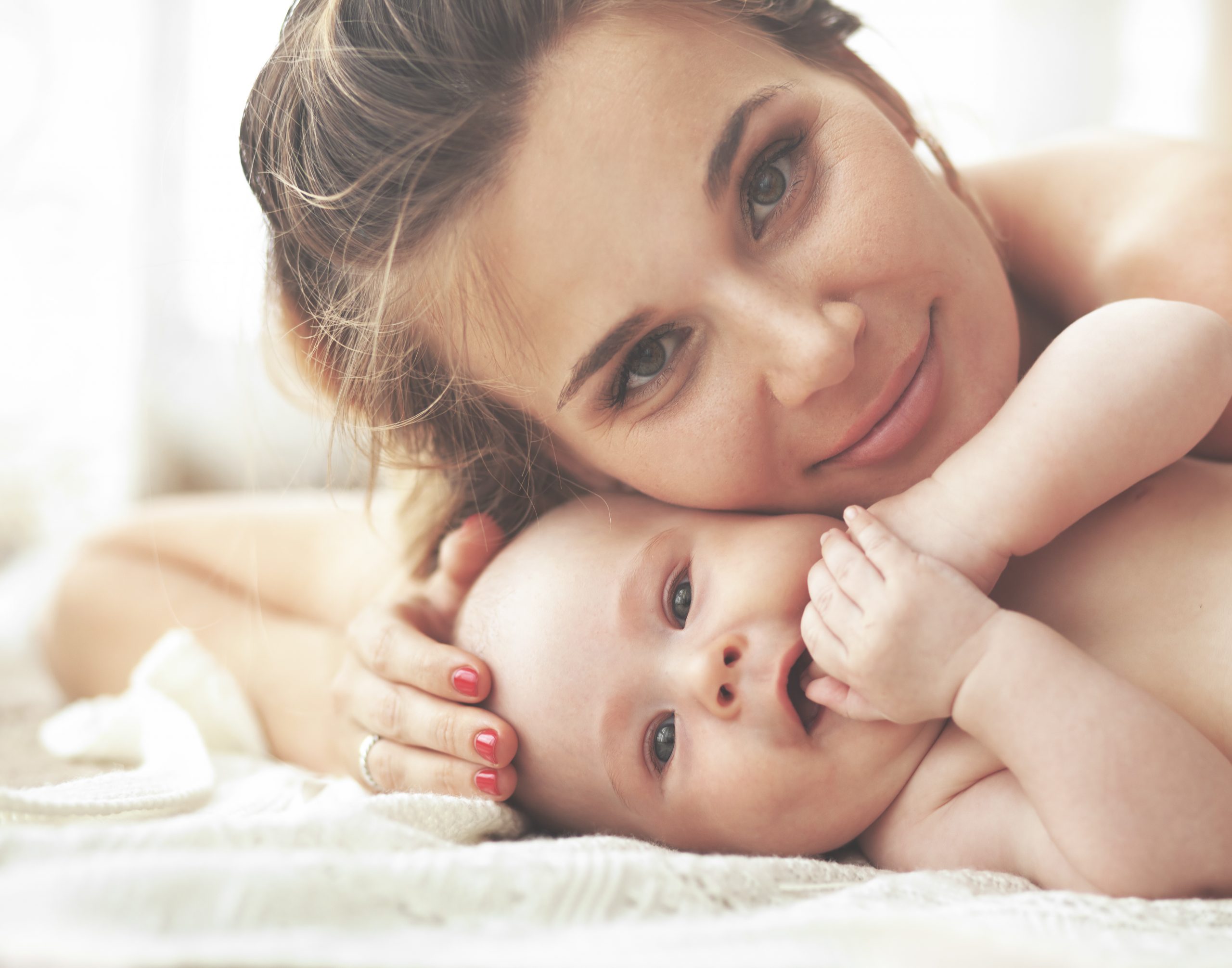 Smiling woman gently laying head on smiling happy baby